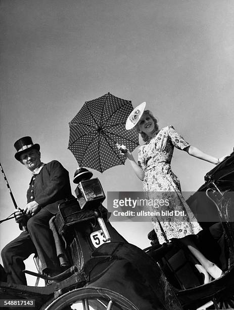 Fashion - summer fashion: young woman in a flowered summer dress with hat and a polka-dotted umbrella in a carriage - 1939 - Photographer: Sonja...