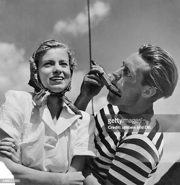 Fashion - summer fashion: young woman with a headscarf in a white pique suit and the man in a striped sweater with harmonica models: Steinhardt -...