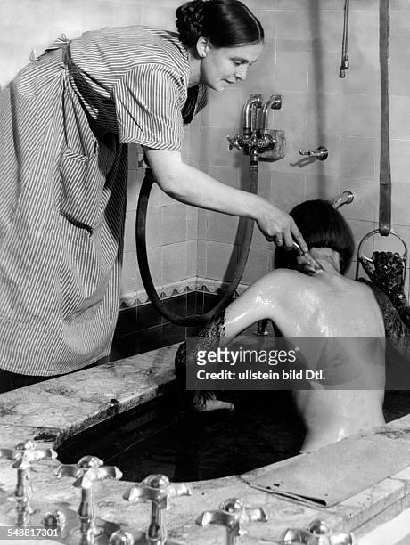 Bad Pyrmont : A woman is rinsed with clean water after a Moor Mud Bath - 1938 - Photographer: Hedda Walther - Published by: 'Die Dame' 12/1938...