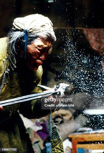 Mongolia, one of the last old shaman in the province of Khoevsgoel lighting her traditional pipe.