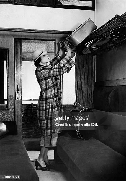 German Empire : Young woman lifts her baggage on the luggage rack in the train - Photographer: Malina - Published by: 'Die Dame' 11/1935 Vintage...