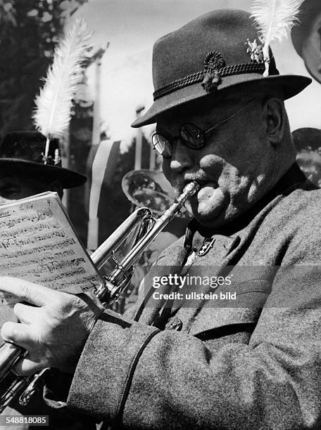 Germany Kingdom Bavaria Munich: Munich Beer Festival: a musician playing in a traditional band blowing the trumpet - 1934 - Photographer: Wolf...