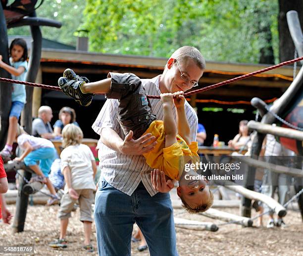 Junger Vater spielt mit Sohn auf einem Kinderspielplatz