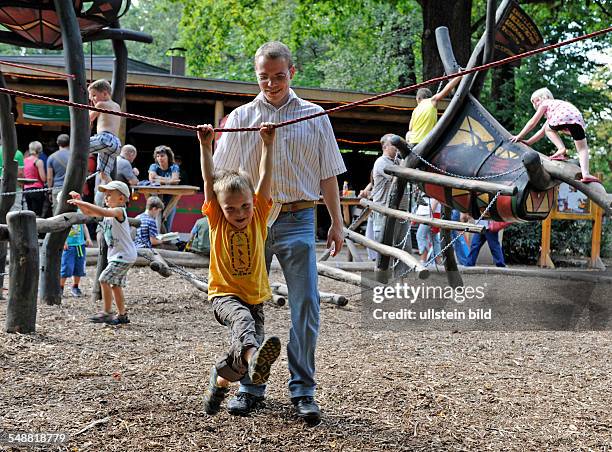 Junger Vater spielt mit Sohn auf einem Kinderspielplatz