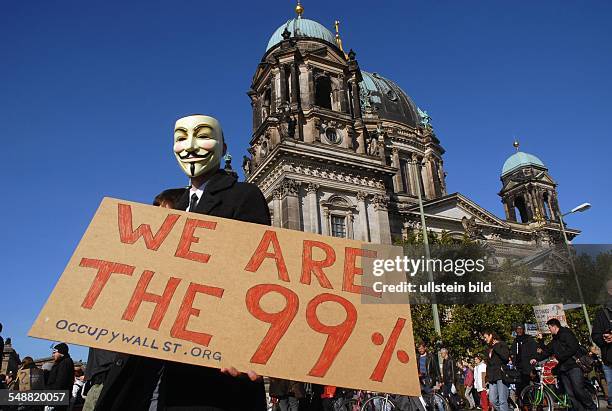 Protestaktion gegen die Finanzbranche, Demonstrant mit Maske und Plakat We are the 99 % vor dem Berliner Dom