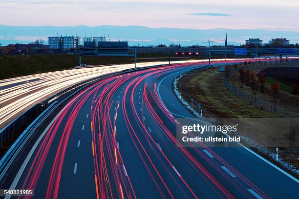 Viele Autos fahren bei Nacht auf einer Autobahn und erzeugen Lichtspuren.