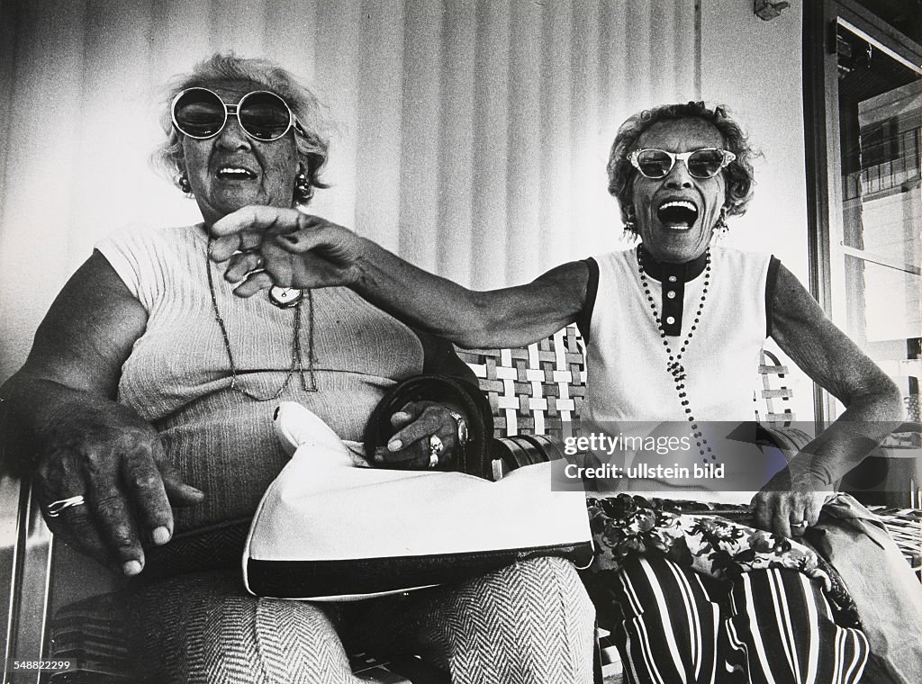 USA, Florida, Miami: Anna Kronenfeld and Sadye Weiss share a joke on the porch in front of the George Washington Hotel on Collins Avenue.