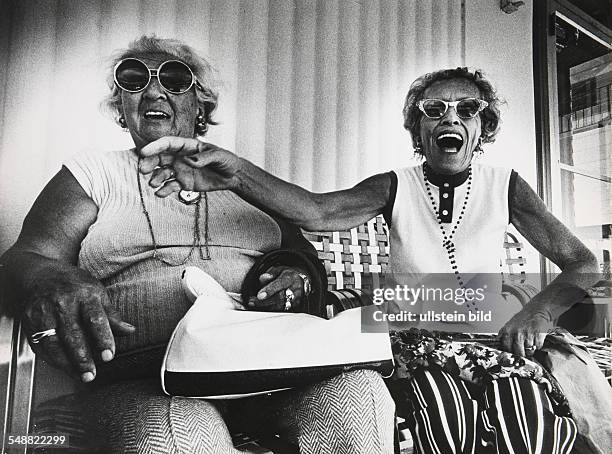 Florida, Miami: Anna Kronenfeld and Sadye Weiss share a joke on the porch in front of the George Washington Hotel on Collins Avenue.