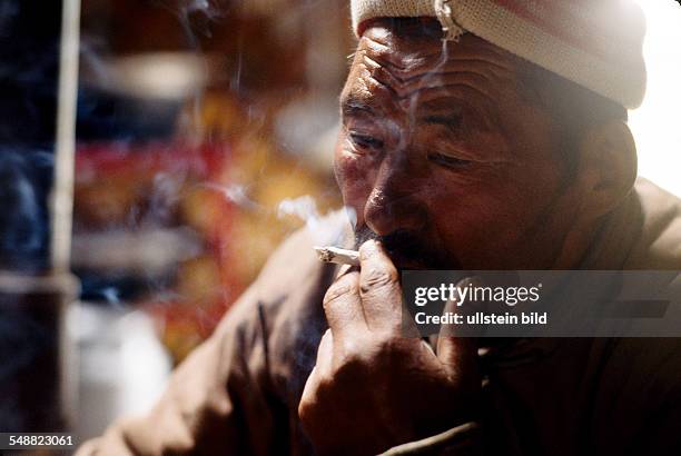 Mongolia, a man smoking a hand volled cigarette in his Jurt in the province of Khoevsgoel.