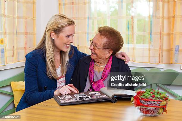 Granddaughter and grandmother are looking at a photo album -