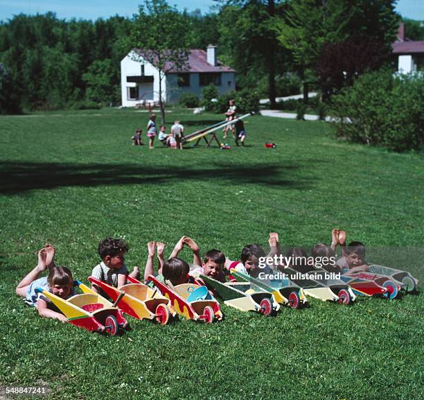 Children with wheel barrows in the garden - 1960s