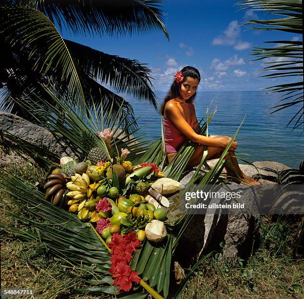 Seychelles - girl with red Frangipani blossom in her hair and friut decoration at the beach - um 1990