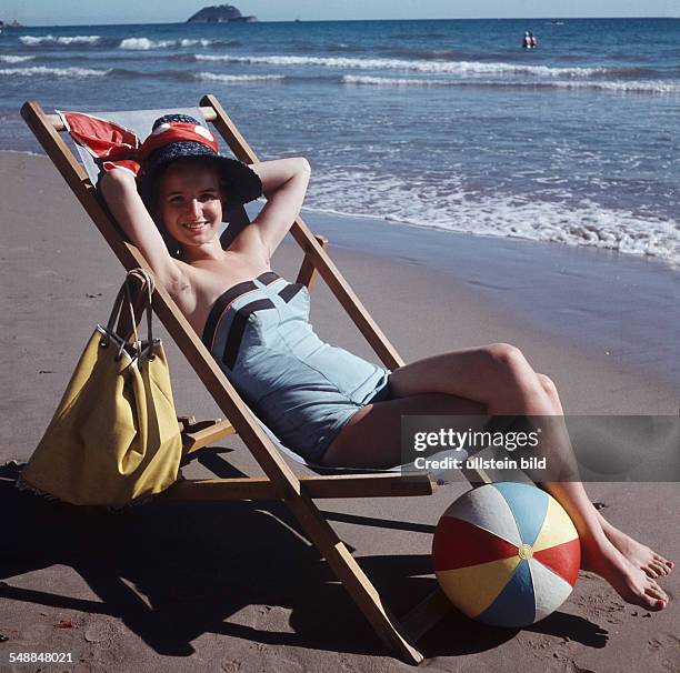 Woman lying on a deck chair at the beach - 1950s