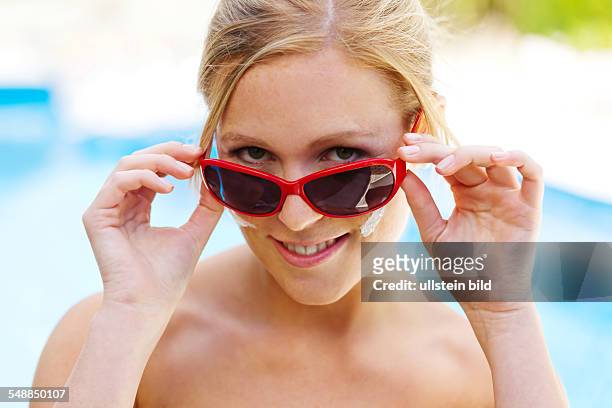 Young woman with sun glasses and suntan lotion -