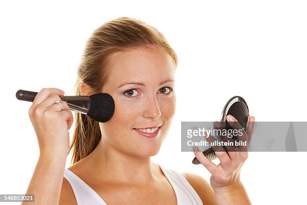 Young woman with powder brush and mirror -