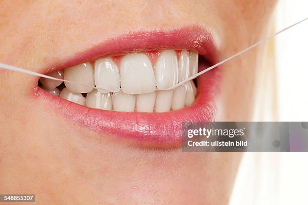 Woman using dental floss to clean her teeth