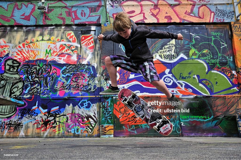 Germany North Rhine-Westphalia Cologne - boy with skateboard in front of a wall with graffity - 18.06.2011