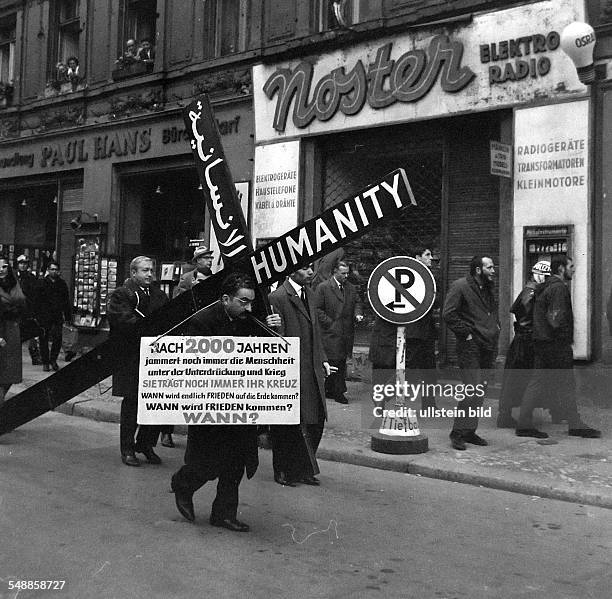 Germany Berlin - A Lebanese businessman carries a cross to the Checkpoint Charly in Berlin, protesting the inhumanity of mankind