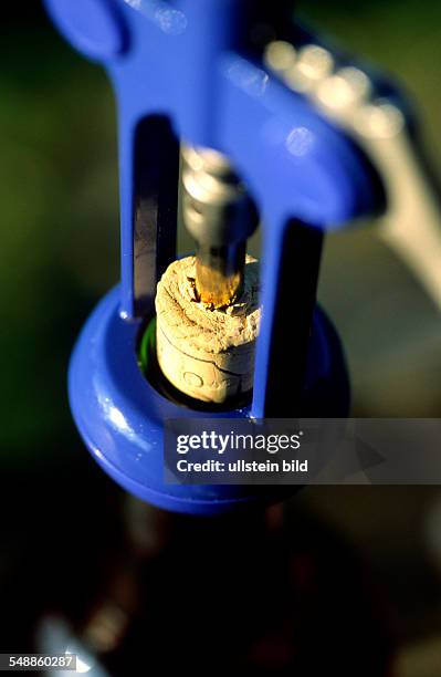 Uncorking in a bottle of wine with a blue corkscrew