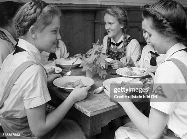 League of German Girls, girls at a meal in a communal accommodation of the 'Kinderlandverschickung' Maedchen Zoepfe hochgesteckte Hochfrisur -...