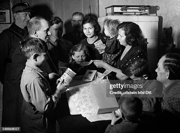 Family with many children is unpacking a Christmas parcel sent by the winter relief - Photographer: Herbert Hoffmann - 1937 Vintage property of...