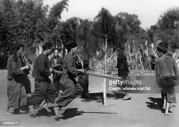 China: A New Year - custom: Indigenous men of the Lahu - people dance around an implanted conifer and play mouth organ - ca. 1942 - Photographer:...
