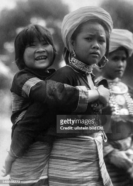 China: The New Year - celebrations: Two young girls of the Lahu - people at the festivity of the New Year's Day, embracing each other from the back -...
