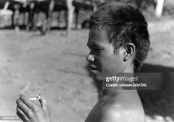 China: A New Year - custom of the Lahu - people: A man determines 'Trial by ordeal' of the god using a chickenbone - ca. 1942 - Photographer: Hugo...