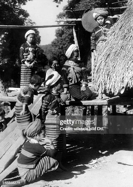 China: The New Year - celebrations: Women of the Lahu - people wearing festive costumes on a platform of a house - ca. 1942 - Photographer: Hugo...