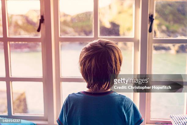 boy looking out of window - six year old stock pictures, royalty-free photos & images
