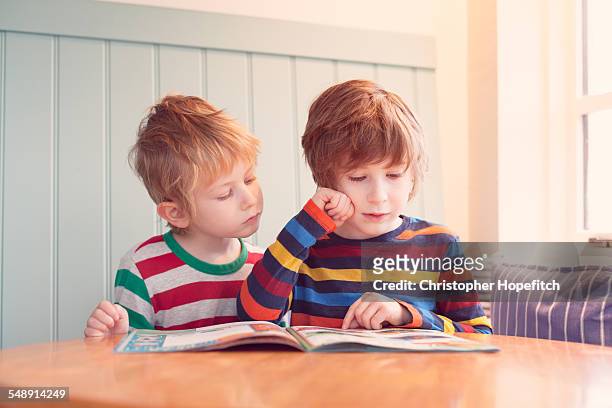 young brothers reading - magazines on table bildbanksfoton och bilder