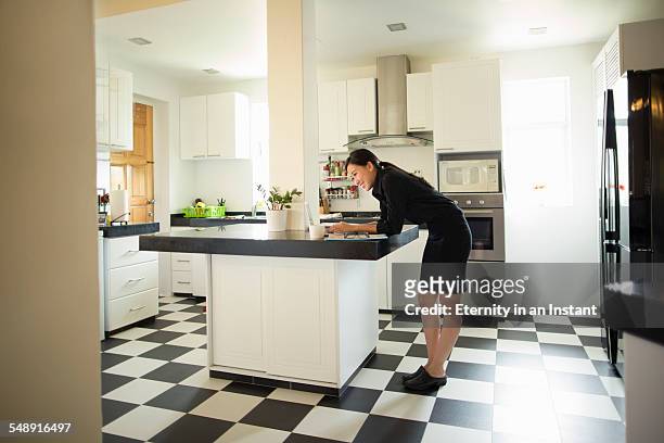 young woman on laptop in kitchen - bending over in skirt stock-fotos und bilder