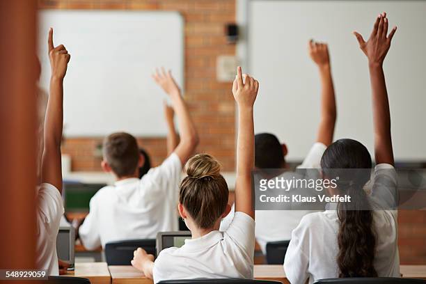 school students with raised hands, back view - school uniform stock pictures, royalty-free photos & images