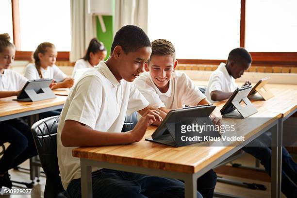 2 students looking on tablet in classroom - school tablet stock-fotos und bilder
