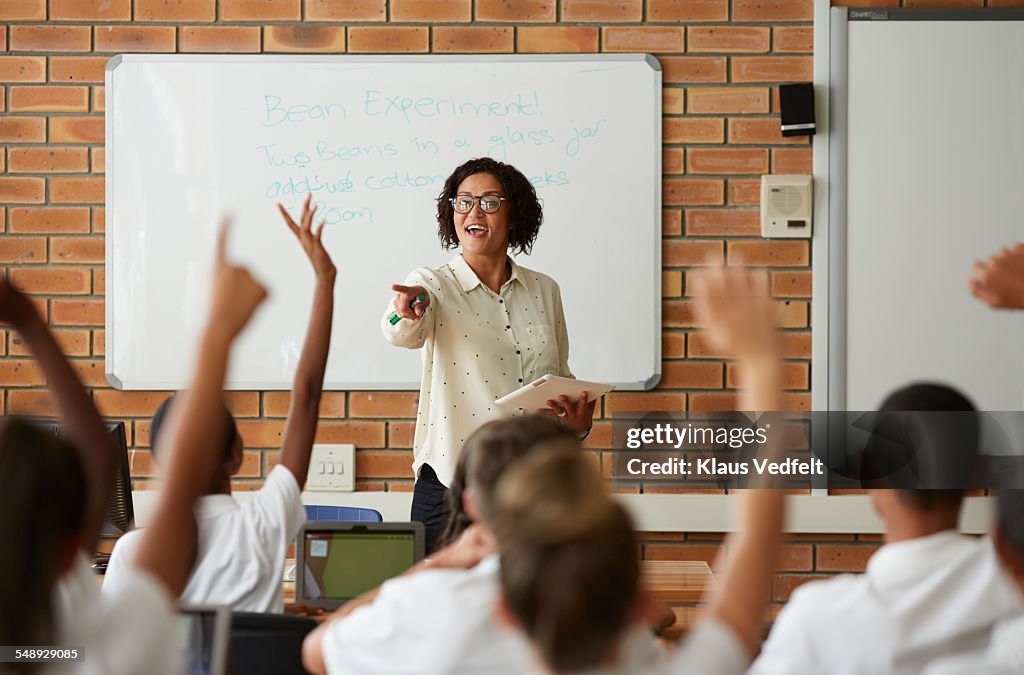 School teacher in front of class with raised hands