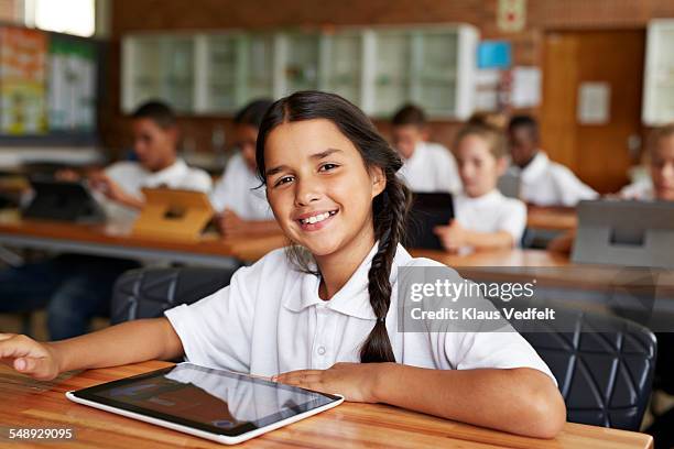 portrait of cute schoolgirl w. tablet in classroom - uniforme escolar - fotografias e filmes do acervo