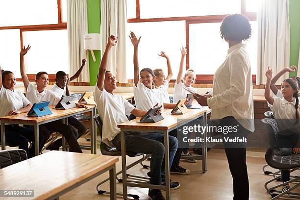 Laughing school class with raised hands