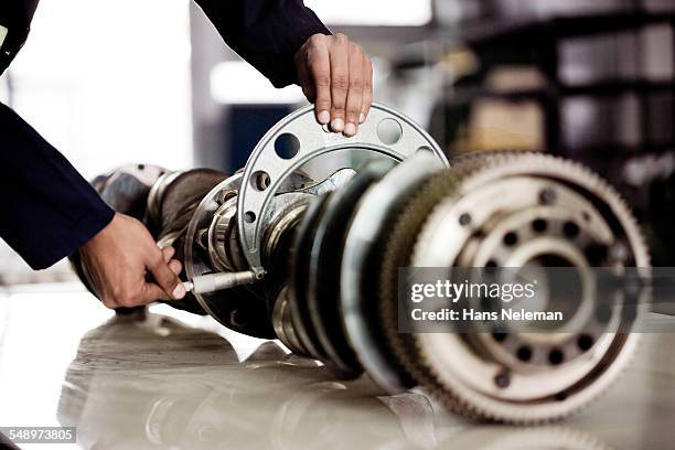 mechanic examining metal piece in a repair shop - machinery fotografías e imágenes de stock