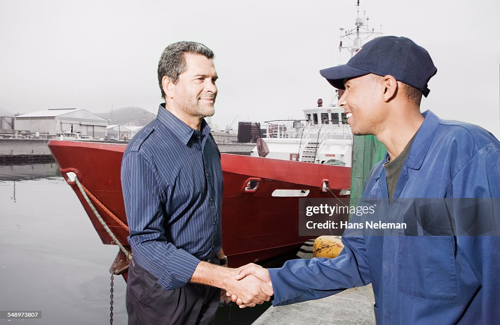 Two workers handshaking, outdoors