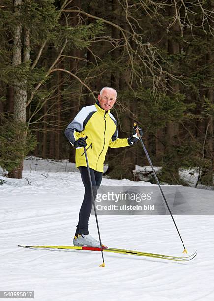 Senior im Winter auf Schnee beim Langlauf mit Skiern