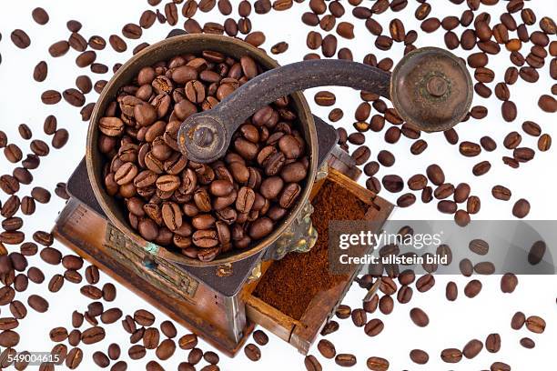 Viele Kaffeebohnen liegen neben einer Kaffeemühle. Frisch gemahlener Kaffee.