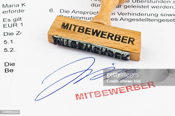 Ein Stempel aus Holz liegt auf einem Dokument. Aufschrift Mitbewerber