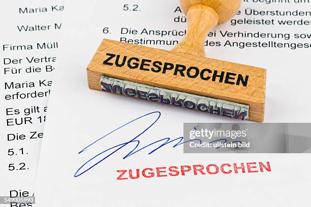 Ein Stempel aus Holz liegt auf einem Dokument. Aufschrift Zugesprochen