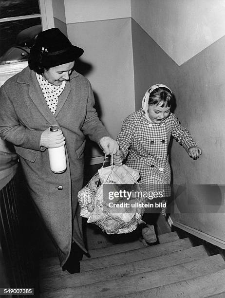 Mother and child back from shopping with heavy filled string bag lete fifties