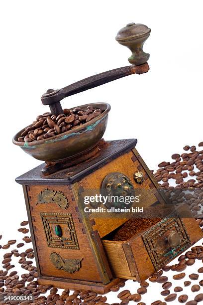 Viele Kaffeebohnen liegen neben einer Kaffeemühle. Frisch gemahlener Kaffee