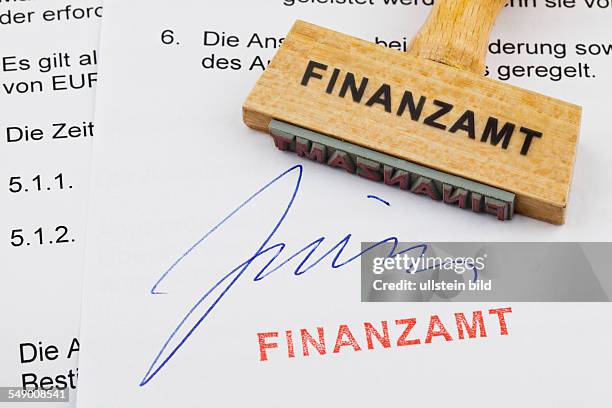 Ein Stempel aus Holz liegt auf einem Dokument. Deutsche Aufschrift: Finanzamt