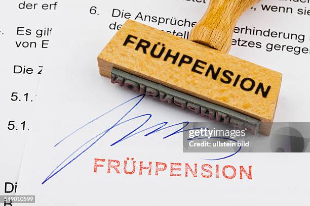 Ein Stempel aus Holz liegt auf einem Dokument. Deutsche Aufschrift: Frühpension