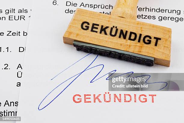 Ein Stempel aus Holz liegt auf einem Dokument. Deutsche Aufschrift: gekündigt