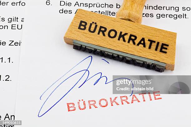 Ein Stempel aus Holz liegt auf einem Dokument. Deutsche Aufschrift: Bürokratie