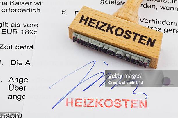 Ein Stempel aus Holz liegt auf einem Dokument. Deutsche Aufschrift: Heizkosten